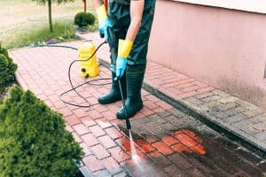 Man cleaning red, concrete pavement